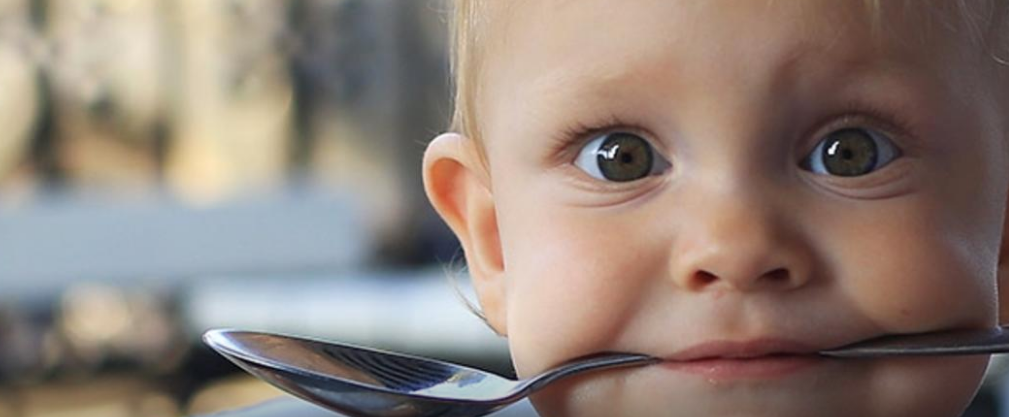 Bebé cogiendo una cuchara con la boca